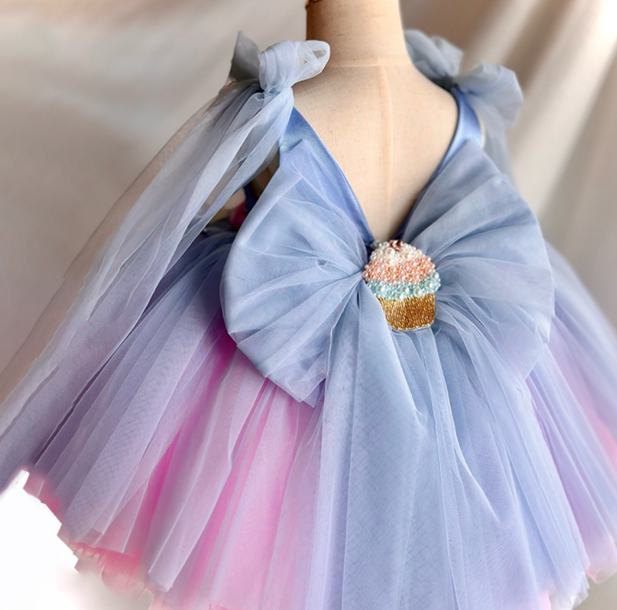 Mannequin wearing a pastel-colored tulle dress with a cupcake brooch.