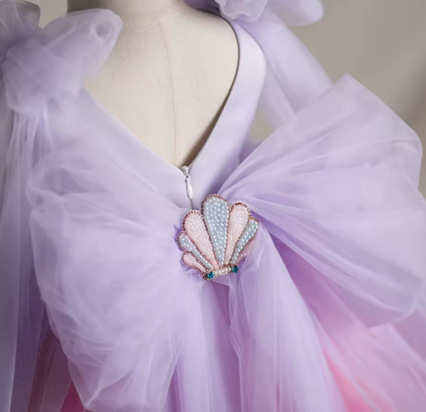 Mannequin wearing a light purple dress with a decorative shell brooch.