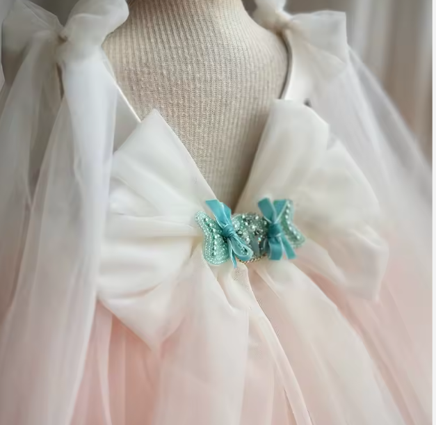 White dress with a large bow and turquoise embellishments on a mannequin.