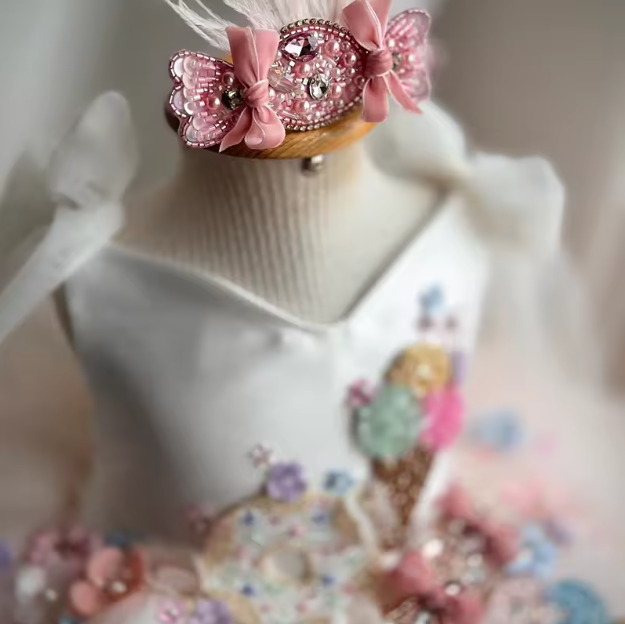 Decorative headband with pink bow and embellishments on a mannequin.