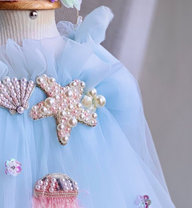 Light blue dress with starfish and shell decorations on a mannequin.
