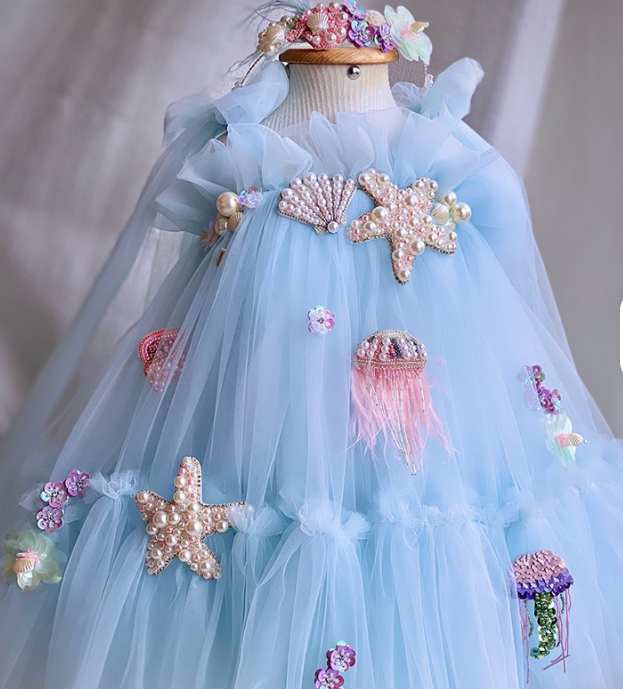 Light blue dress with sea-themed decorations on a mannequin against a neutral background