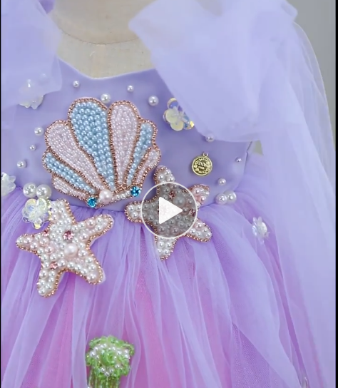 Purple dress with shell and starfish decorations on a mannequin.