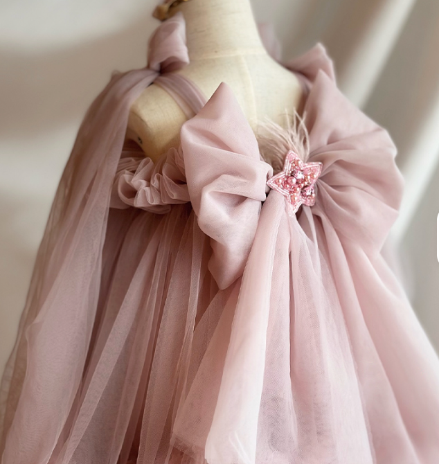 Mannequin wearing a pink dress with a large bow and floral detail on a plain background