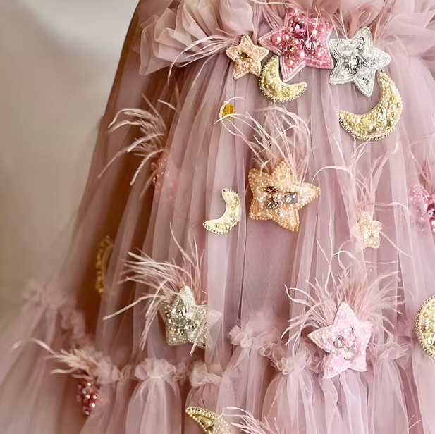 Pink tulle fabric with decorative stars and moons on a plain background