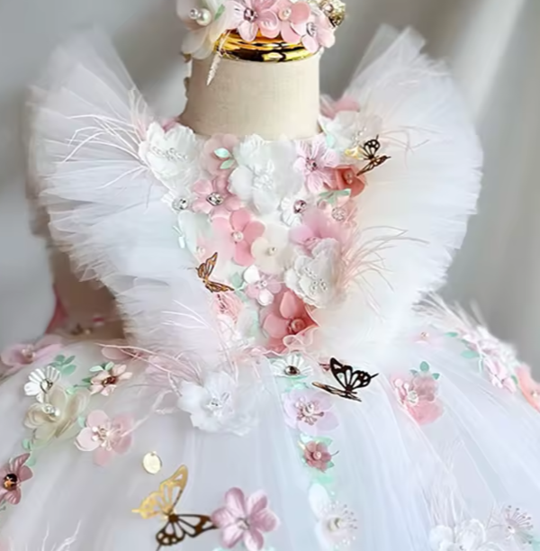 Delicate white dress with floral and butterfly embellishments on a mannequin.