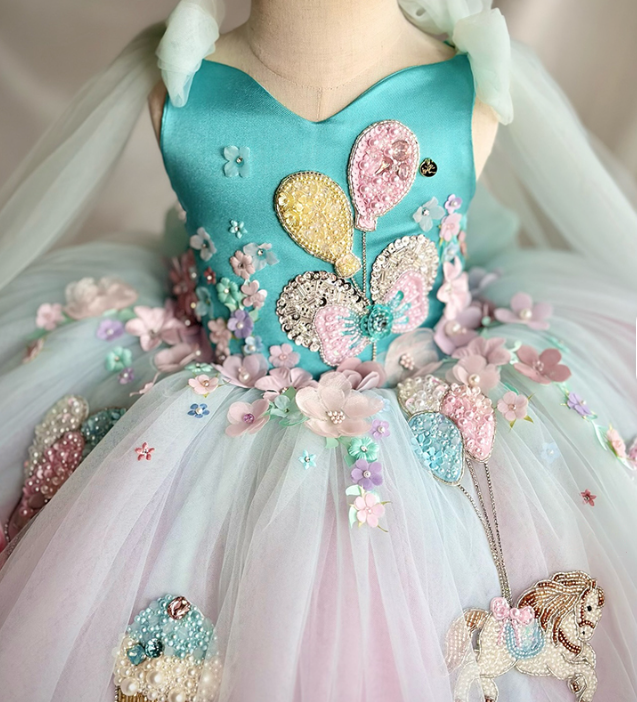 Decorative dress with floral and animal-themed embellishments on a plain background