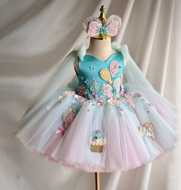 Children's dress with floral and balloon designs on a mannequin against a neutral background