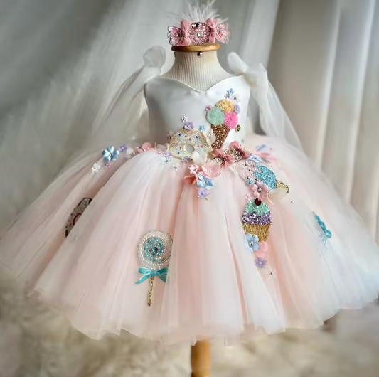 Delicate pink dress with floral and ice cream cone decorations on a mannequin against a soft white background.