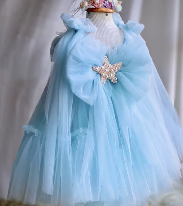 Light blue dress with a star-shaped brooch on a mannequin against a neutral background