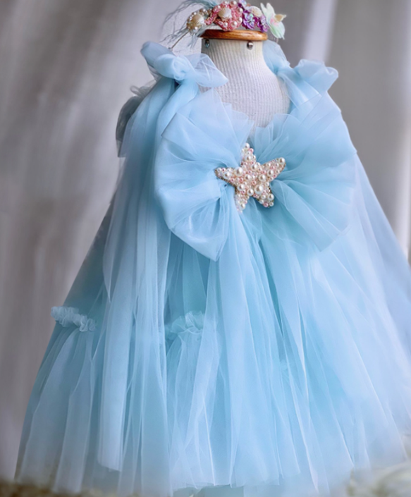 Light blue dress with a starfish brooch on a mannequin against a neutral background