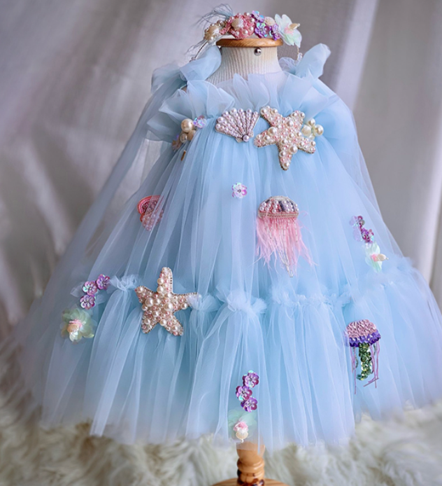 Light blue dress with starfish and jellyfish decorations on a mannequin against a neutral background