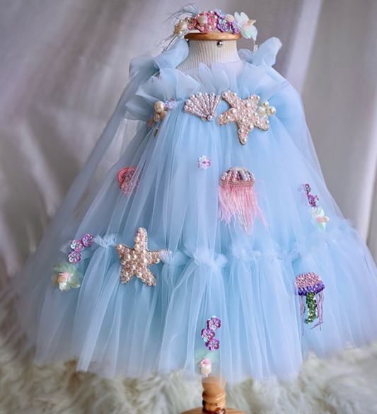Light blue dress with starfish and jellyfish decorations on a mannequin against a neutral background