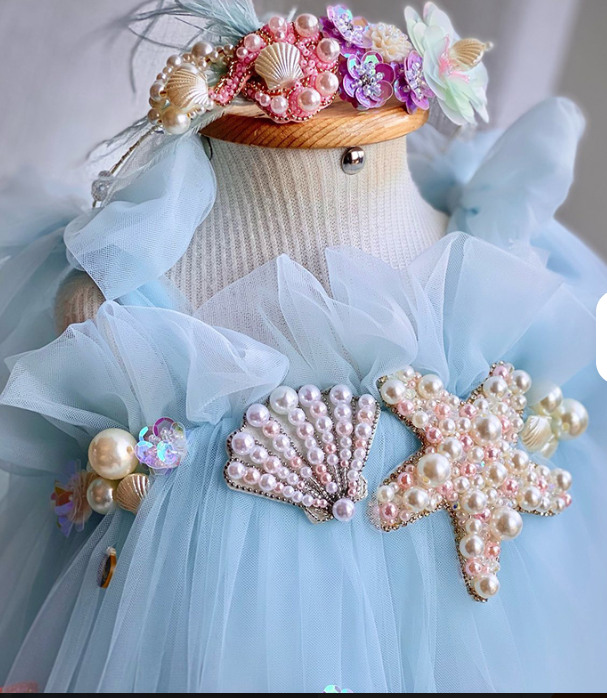Mannequin wearing a light blue dress with pearl embellishments on a neutral background