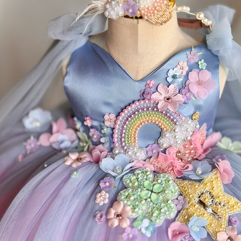 Pastel-colored dress with floral and rainbow embellishments on a mannequin.