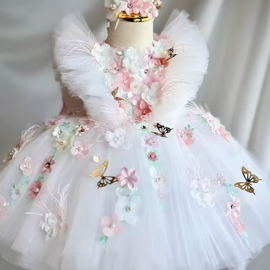 Delicate children's dress with floral and butterfly details on a mannequin against a neutral background.