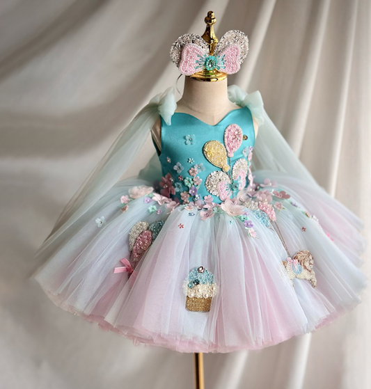 Children's dress with floral and balloon designs on a mannequin against a neutral background